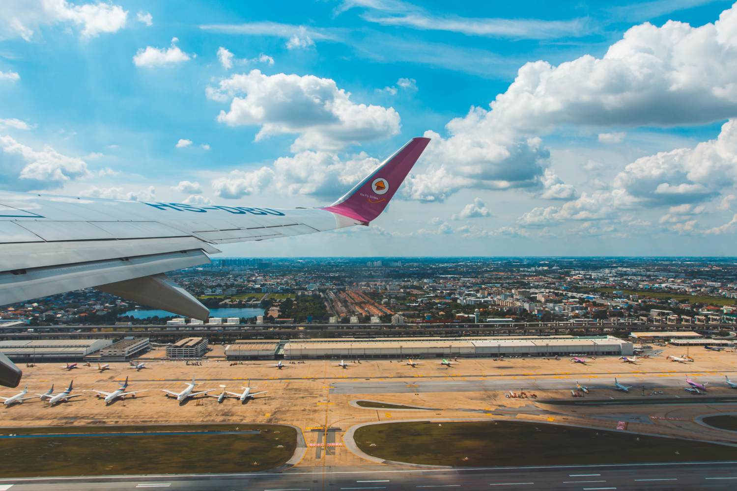 Frachtflugzeug startet über einem Flughafen mit Containern und Hallen.